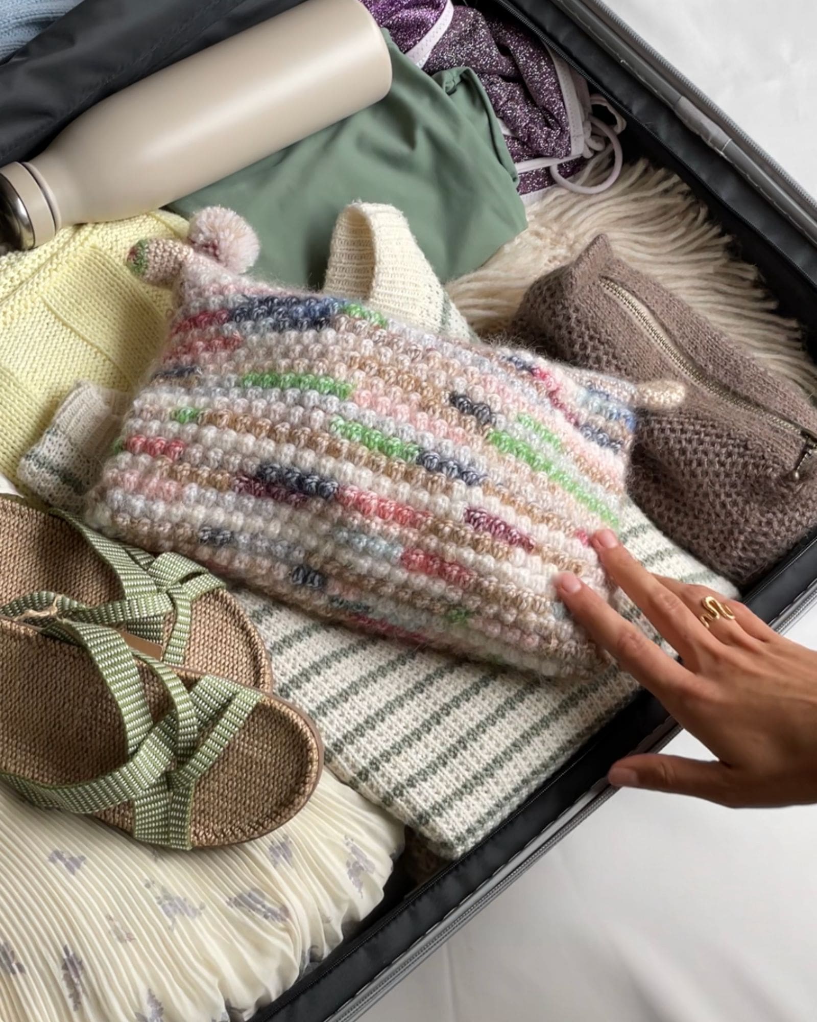 En person har pakket en kuffert til sin sommerferie. Forrest ligger en Shell clutch med strikkepinde osv. til rejsen.